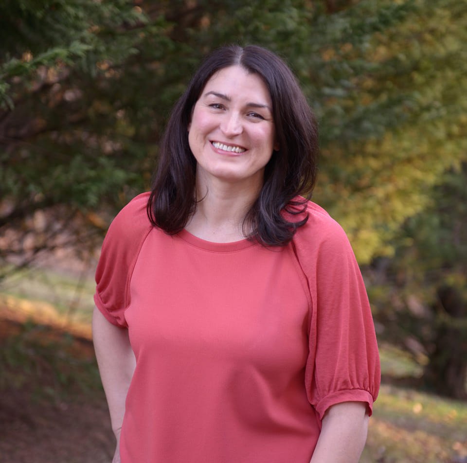 Photo of Meg Ricks wearing rose top, long dark brown hair