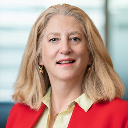 Headshot of Andrea Chamblee wearing a red blazer, yellow shirt. Long blonde hair